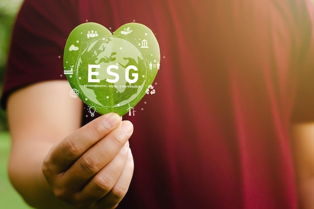 Green Energy ESG Renewable and Sustainable Resources in environmental protection and ecology Close-up of a young man holding a heart-shaped green leaf present to the camera