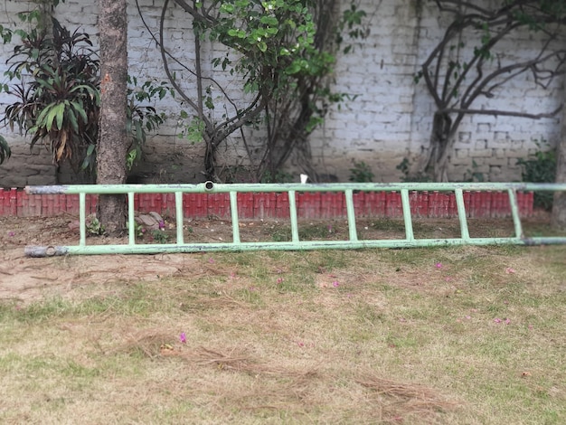 Photo a green fence with a red border and a white brick wall with a tree in the background