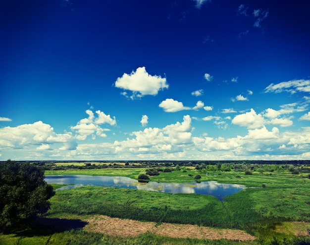 Green field with small lake in summer instagram stile