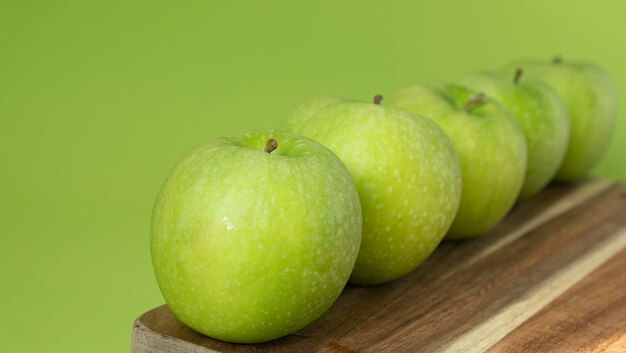 Green and fresh apples on wooden background and on green color