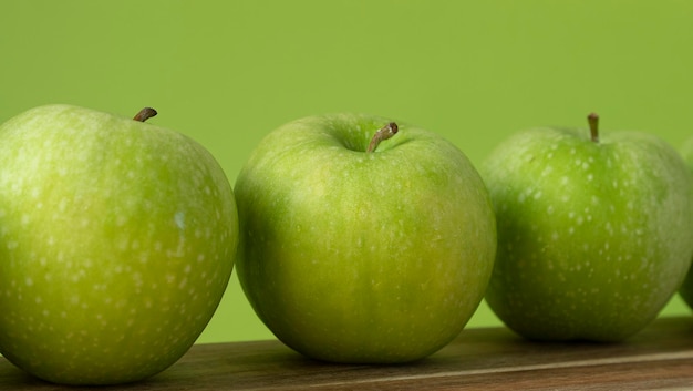 Green and fresh apples on wooden background and on green color