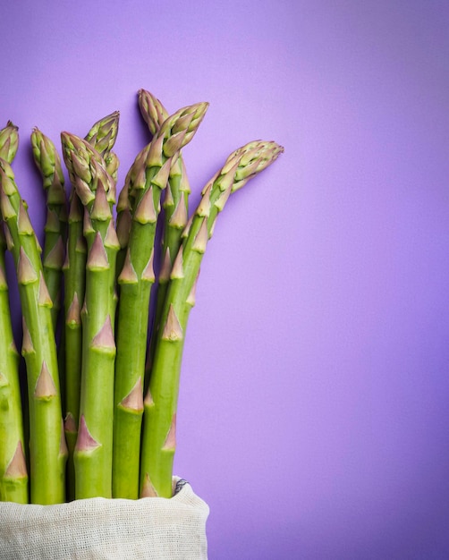 Green fresh asparagus on purple background