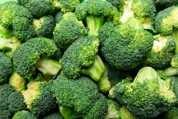 Green fresh broccoli background close up on colored table. Vegetables for diet and healthy eating. Organic food