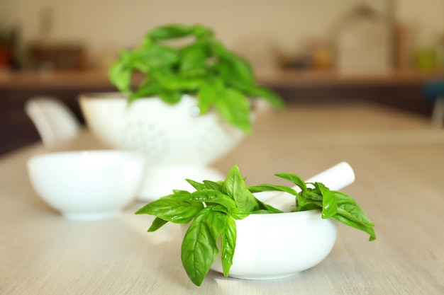 Green fresh organic basil in ceramic mortar on kitchen table