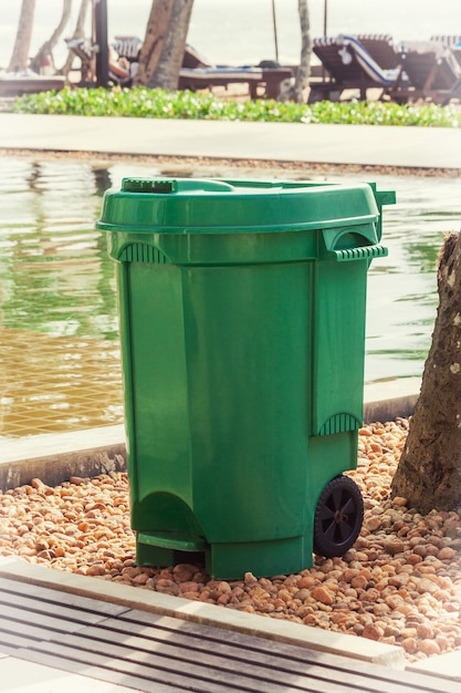 Green Garbage Trash Bin near Swimming Pool extreme closeup.