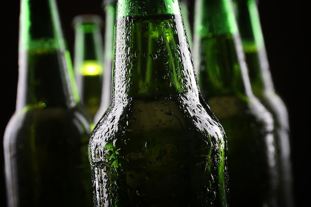 Green glass bottles of beer on dark background close up