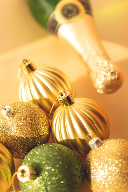 Green and gold  Christmas baubles on a beige background festive xmas composition with a bottle of champagne with selective focus