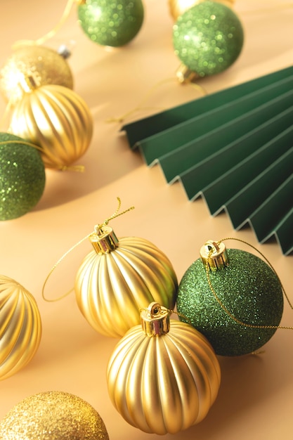 Green and gold Christmas baubles and a paper fan on a beige background festive xmas composition