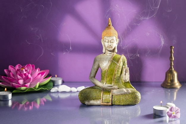 Green and golden buddha statue in meditation on light purple background with copy space