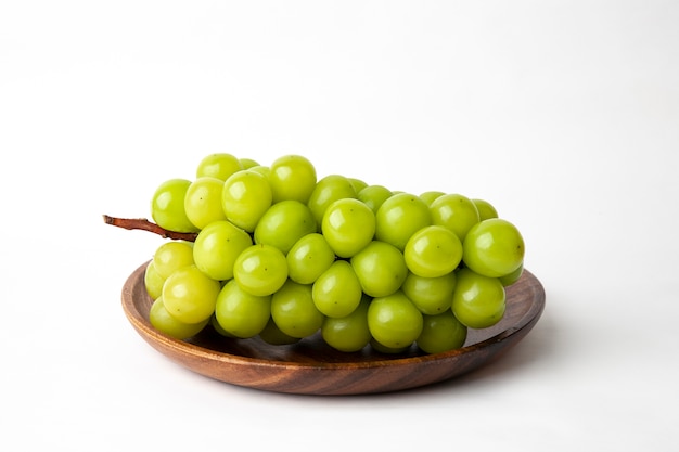 Green grapes on a wooden plate