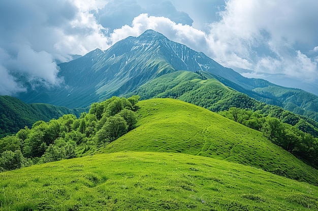 A green grassy hill with mountains in the background and clouds above it green hills a photo of an