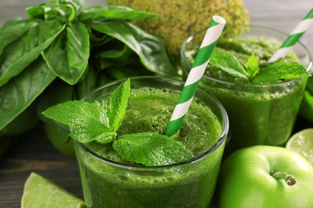 Green healthy juice with fruits and herbs on table close up