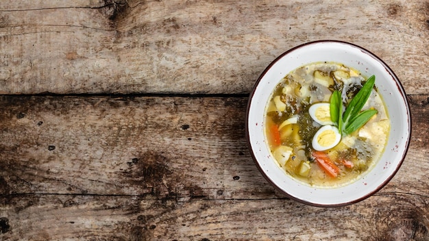 Green herb cream soup in the bowl Sorrel soup with egg potatoes carrots parsley Long banner format top view