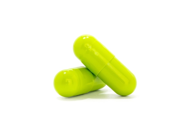 Green herbal medicine capsules on white