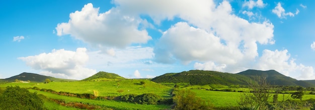 Green hills under a blue sky with clouds in Sardinia Italy