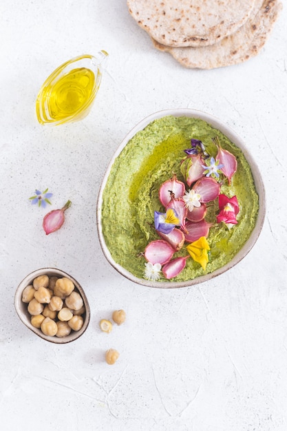 green hummus bowl with baked radish and edible flowers