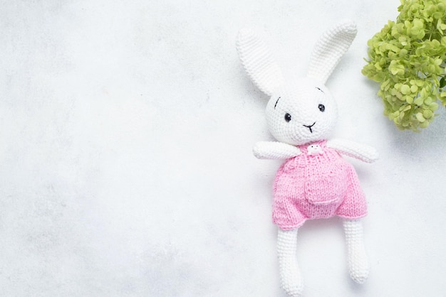 Green hydrangeas and homemade knitted toy hare on a light background Postcard