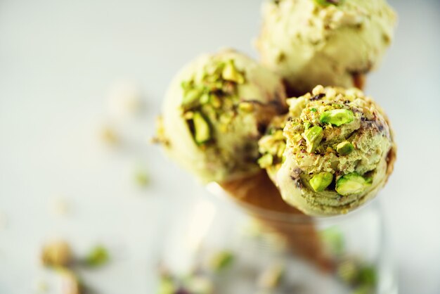 Photo green ice cream in waffle cone with chocolate and pistachio nuts on grey stone . summer food concept, copy space. healthy gluten free ice-cream.