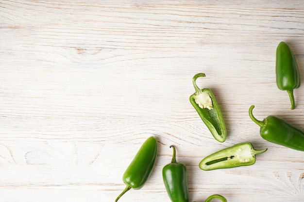 Green jalapeno peppers wooden background, place for text, top view.