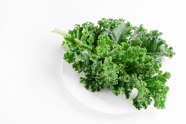 Green kale cabbage leaves on white background. Textured leaves in white plate. Top view and copyspac