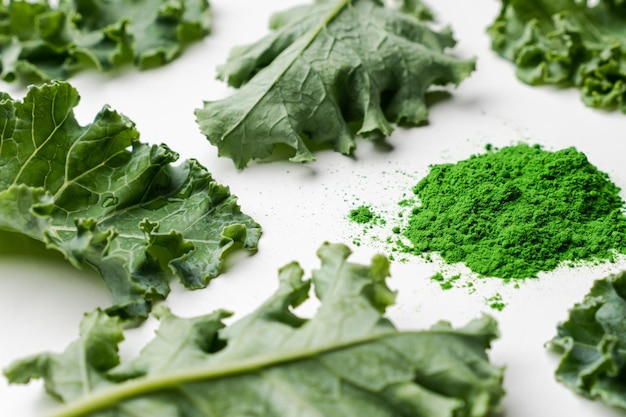 Green leaves of kale and kale powder on white background