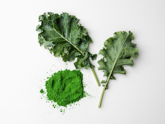 Green leaves of kale and kale powder on white background