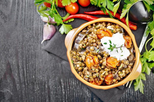 Green lentils stewed with eggplant, tomatoes, garlic and spices, sour cream sauce with a sprig of thyme in a bowl