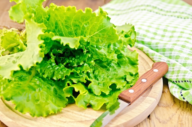 Green lettuce with a knife, napkin on wooden board