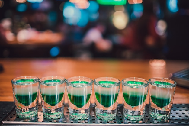 Green liquid in shot glasses standing on the counter.