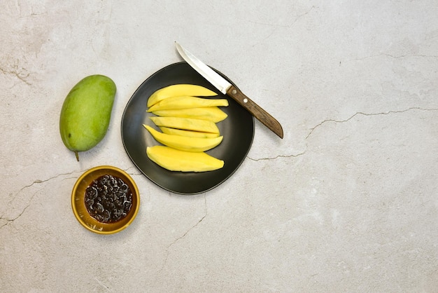 Green mango and ready to eat on black dish with sweet fish sauce on grungy cement floor