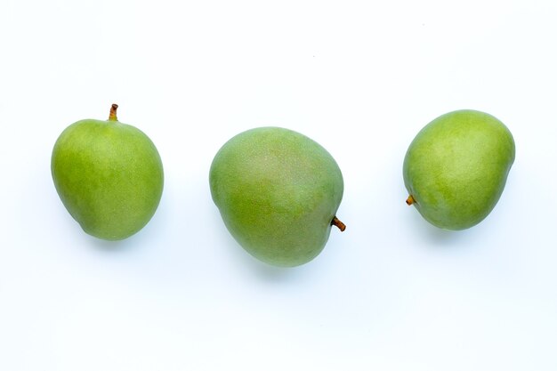 Green mangoes on white surface