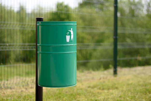 A green metal trash bin in the park or outside of a public utility buildingxA