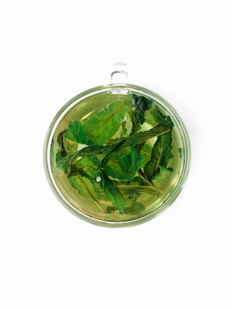 Green mint tea in a glass cup with mint leaves on a white background isolated top view