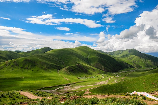 A green mountain landscape with a blue sky and clouds