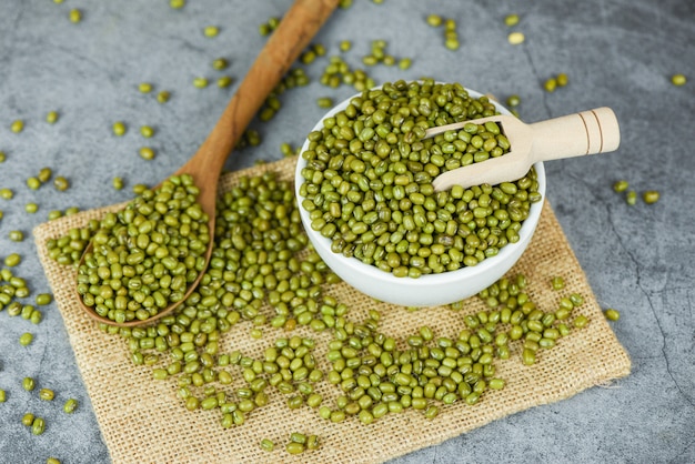 Green mung beans in bowl and wooden spoon on the sack 