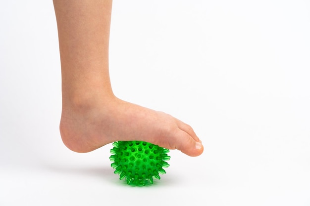 Green needle ball for massage and physical therapy on a white background with a childs foot the