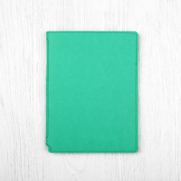 Green notebook on white wooden table top view