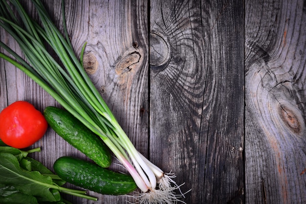 Green onions, tomato and cucumber on a gray wooden background