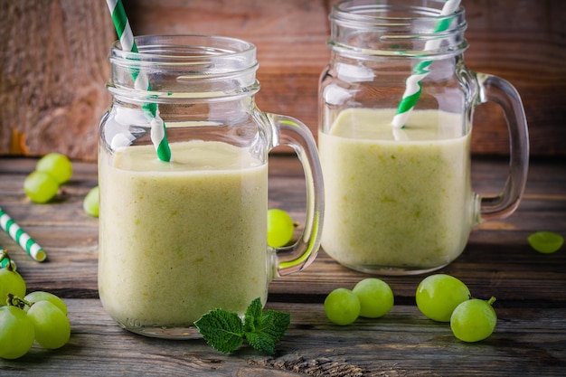 Green organic detox grape smoothie in glass mason jar on wooden rustic background