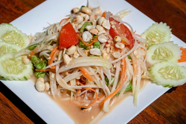 Green papaya salad or Som tum Thai in white plate closeup Thai cuisine somtum salad popular food in Thailand