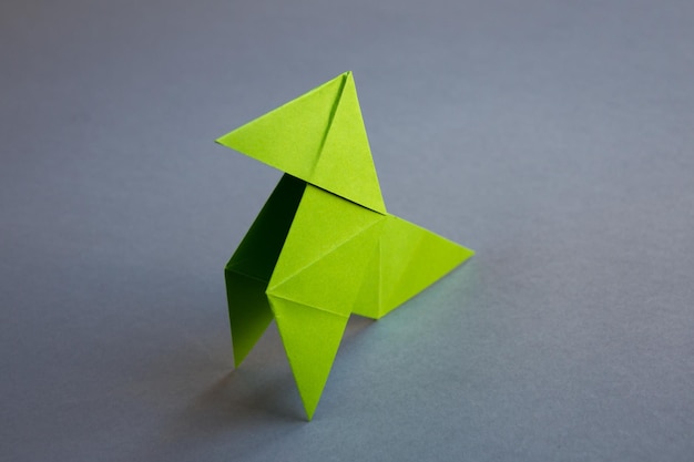 Green paper hen origami isolated on a grey background