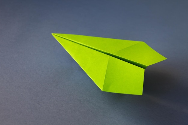 Green paper plane origami isolated on a grey background