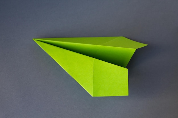 Green paper plane origami isolated on a grey background