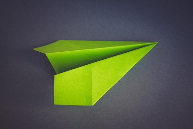 Green paper plane origami isolated on a grey background