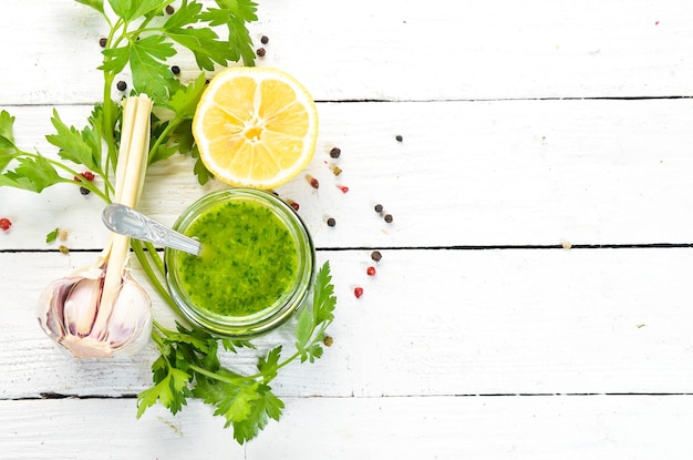 Green parsley sauce Ingredients for chimichurri sauce On a white wooden background Top view free space for your text