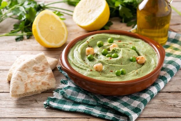 Green pea hummus and pita bread on wooden table