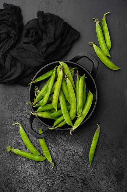 Green pea pod on black dark stone table background top view flat lay