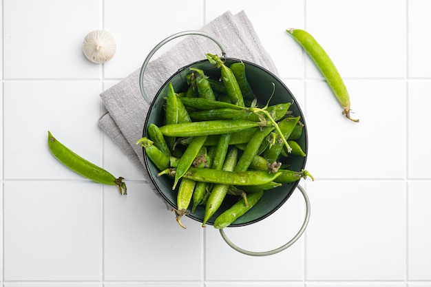 Green pea pod on white ceramic squared tile table background top view flat lay