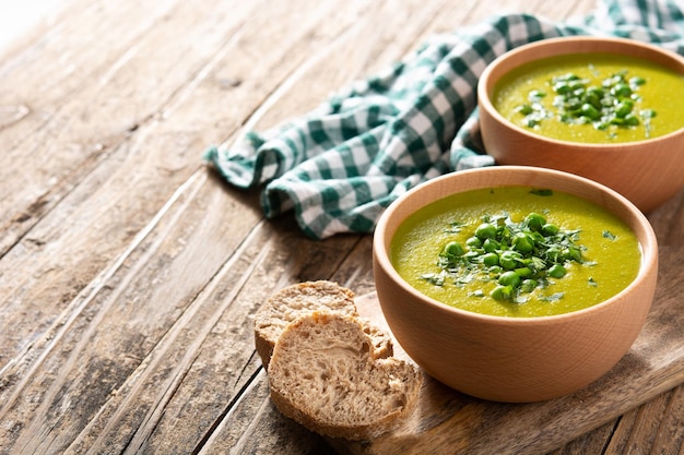 Green pea soup in a bowl on rustic wooden table Copy space