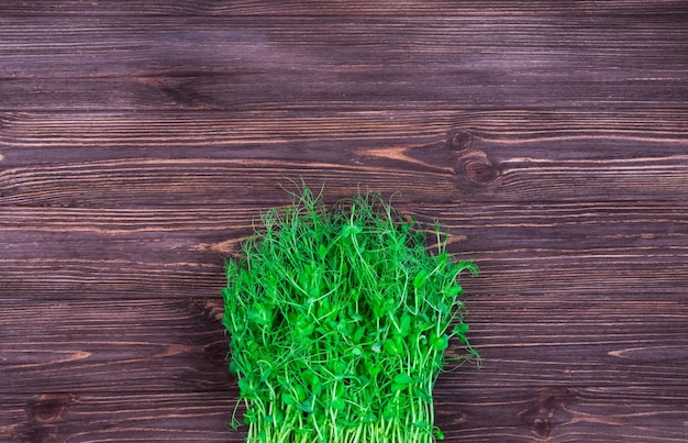 Green pea sprouts on a wooden textured dark background Place for an inscription